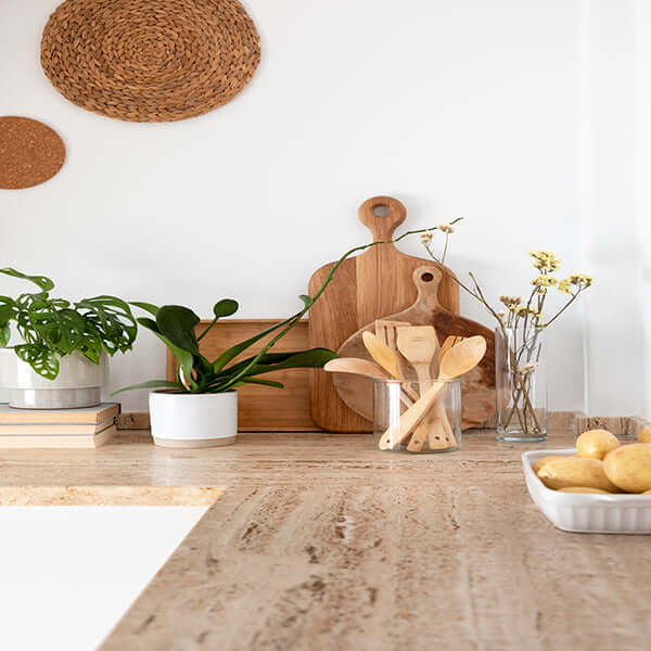 Modern kitchen counter decorated with wooden cutting boards, fresh plants, and rustic utensil holder.